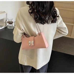 Dettaglio borsa rosa chiaro in pelle PU con fibbia a fiocco e tracolla a catena intrecciata