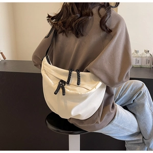 Close-up of a white crescent crossbody bag with minimalist fabric and rope zipper details