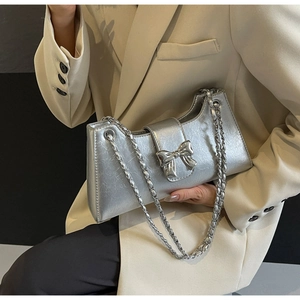 Dettaglio borsa argento in PU con fiocco e tracolla a catena su blazer beige elegante