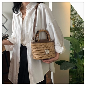 Detail of woven straw handbag featuring bamboo handles and GOOD WEEKEND patch