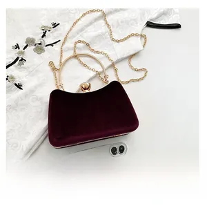 Detail of purple velvet evening clutch featuring gold metal handle and snap closure