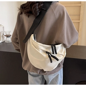 Rear view of model wearing a stylish white crescent crossbody bag with black wide straps