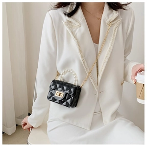 Détail du mini sac gelée noir avec poignée en perles et chaîne dorée sur un mannequin