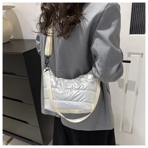Detail of white quilted puffy shoulder bag with glossy metallic texture and adjustable strap