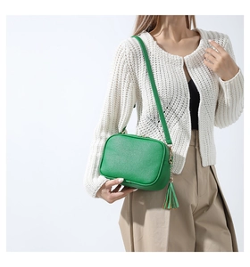 Detail of green crossbody bag showing premium lychee grain leather and tassel zip