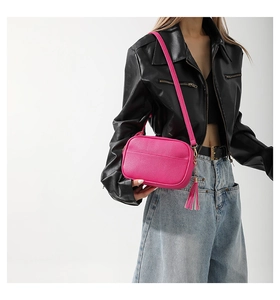 Macro detail of rose pink leather camera bag with tassel and gold hardware