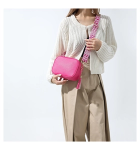Detail of lychee leather crossbody bag in hot pink with jacquard woven shoulder strap