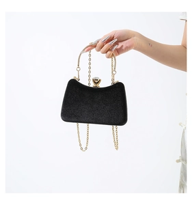 Detail of black velvet clutch bag with crystal buckle and gold chain strap