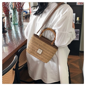 Detail of woven straw handbag with bamboo handle and Good Weekend logo patch