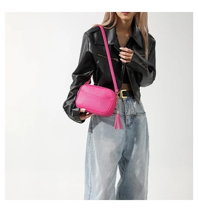 Detail of rose pink crossbody bag with lychee texture and stylish side tassel