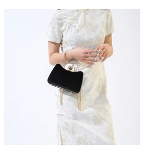 Detail of luxury black velvet evening bag featuring gold handle and crystal jewel clasp