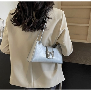 Borsa a spalla argento testurizzata con fiocco metallico indossata da una modella