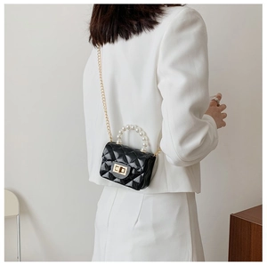 Détail du mini sac en gelée noir brillant avec poignée en perles et chaîne dorée