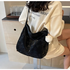 Detailed side view of black velvet shoulder bag with a cute white plush lamb keychain charm