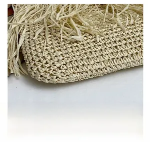 Dettaglio borsa in paglia intrecciata beige con trama all'uncinetto e bordi con frange