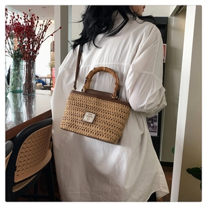Close-up of woven straw handbag featuring vintage bamboo handle and leather logo patch