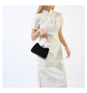 Detail of elegant black velvet clutch bag with gold handle and chain strap for evening wear