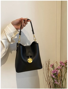 Gros plan détaillé du sac seau en cuir noir grainé avec des finitions métalliques dorées