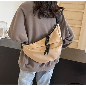 Detail view of khaki crescent nylon crossbody bag with adjustable wide black strap on person
