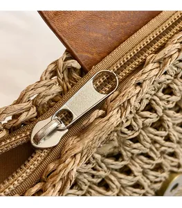 Close-up of a smooth gold metal zipper on a woven straw bag with premium leather trim