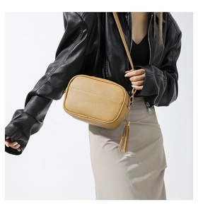 Fashionable camel PU leather crossbody bag with tassel detail shown on model for size
