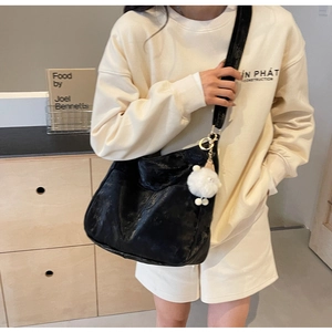 Detail of black PU crossbody bag with plush lamb pendant on wide shoulder strap
