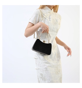 Detail of elegant black velvet evening bag with gold metal handle and wave-shaped design