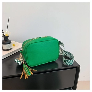 Green leather camera bag with patterned wide strap and decorative tassel charm
