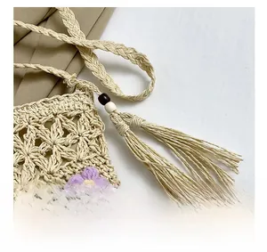 Detailed close-up of straw woven bag with crochet flowers and beaded tassels