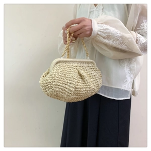 Detail of hand-woven beige straw handbag featuring a round cloud shape and gold chain strap