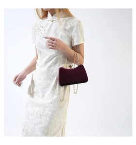 Detail of burgundy velvet evening bag with gold chain and large rhinestone clasp