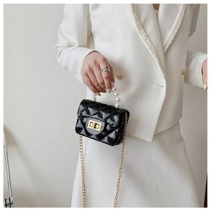 Détail du mini sac noir matelassé avec fermoir doré et élégante poignée en perles