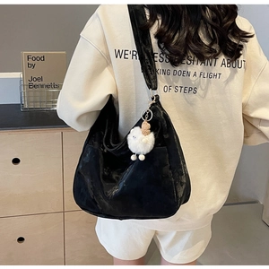 Detail view of large black crossbody bag with smooth texture and cute sheep charm