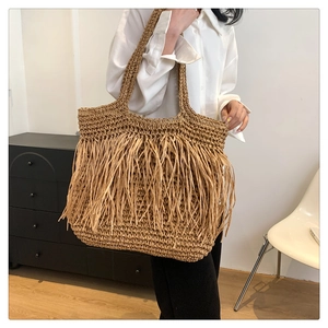 Dettaglio ravvicinato della borsa tote in paglia intrecciata con lunghe frange moda