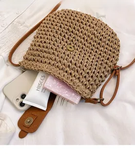 Detail view of woven straw crossbody bag with brown leather strap and magnetic closure