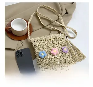 Detail of hand-woven straw crossbody bag with colorful crochet flowers and beaded tassels