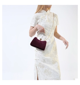 Detailed close-up of velvet handbag with large pearl gold clasp and chain strap