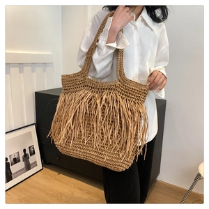 Dettaglio di una borsa tote in paglia con lunghe frange decorative e manici resistenti