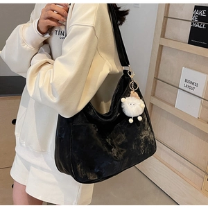 Detail of black PU leather shoulder bag with vintage texture and fluffy white charm