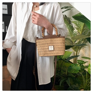 Detail shot of hand-woven straw tote bag with bamboo handles and adjustable leather strap