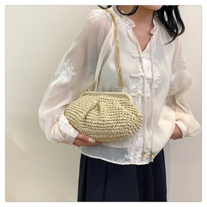 Detail of beige woven straw cloud bag featuring delicate pleats and gold chain strap