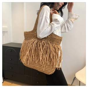 Dettaglio della borsa tote in paglia bohémien con lunghe nappe a frangia e trama intrecciata