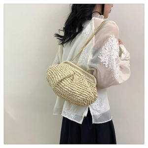 Detail of beige woven cloud bag with stylish gold metal chain strap on model