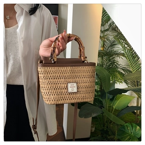 Detail of woven straw handbag featuring bamboo handle and leather Good Weekend tag