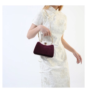 Detail of deep purple velvet evening bag with golden metal handle and diamond clasp