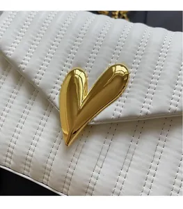 Detail of white PU leather bag with vertical quilting and a large golden heart metal buckle