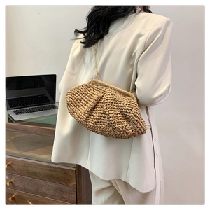 Detail of hand-woven beige clutch bag with soft texture and gold metal chain strap