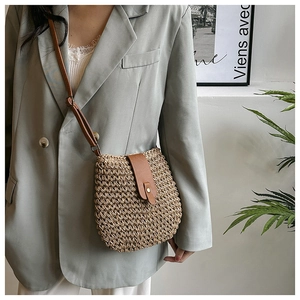 Close-up of woven crossbody bag with brown leather flap and adjustable strap details