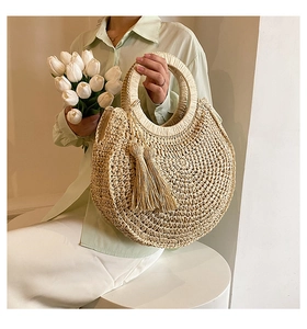 Detailed texture of natural woven straw handbag featuring elegant circular handles and tassels