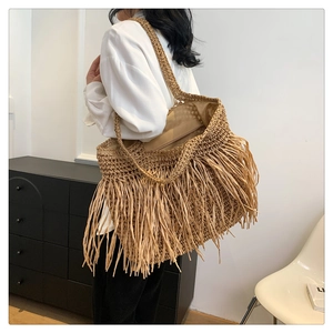Borsa tote in paglia con lunghe frange bohémien indossata da una modella in stile minimal
